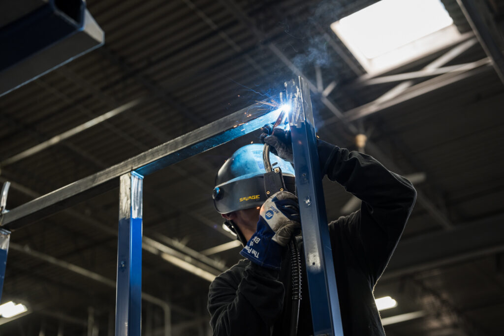 Man welding and repairing a steel rack