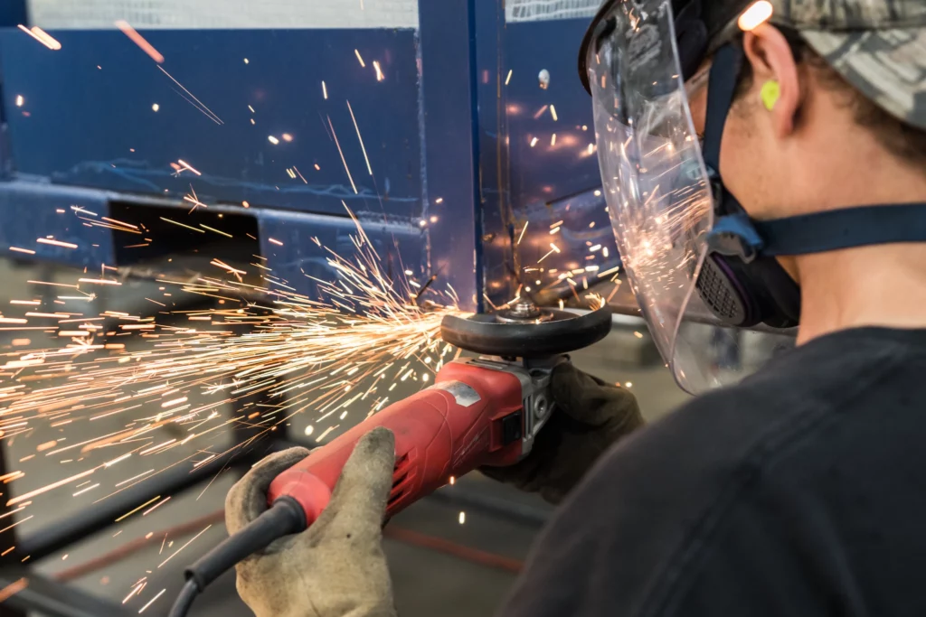 Michigan Industrial Container employee uses an electric cutting tool to repair and modify a steel automotive rack.